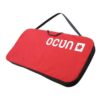 Das Bild zeigt die Ocun Sitcase Bouldermatte. Das kleine rote Crashpad liegt schräg im Bild, man erkennt den Schulterriemen und das Logo am Pad.