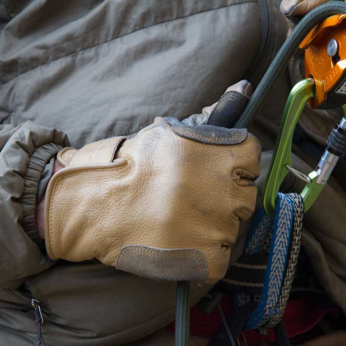 Das Bild zeigt den Metolius Belay Glove beim Abseilen an der Hand eines Kletterers.