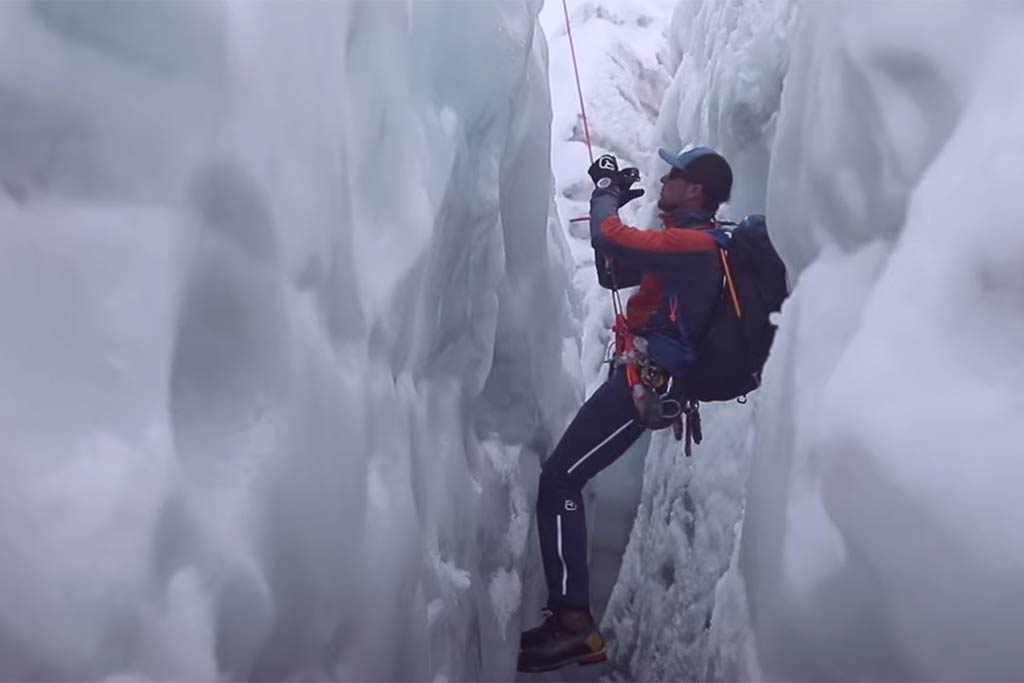 Das bild zeigt einen Bergsteiger bei der Selbstrettung aus einer Spalte mit Prusikschlingen.