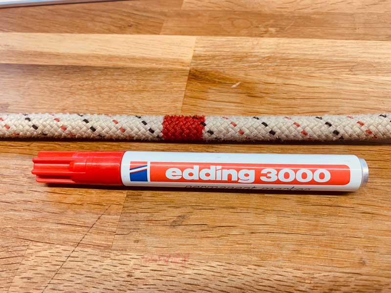Das Bild zeigt ein weißes Statikseil und einen roten Edding 3000 Stift zum Seilmitte markieren. Das Seil hat die entsprechende rote Markierung.