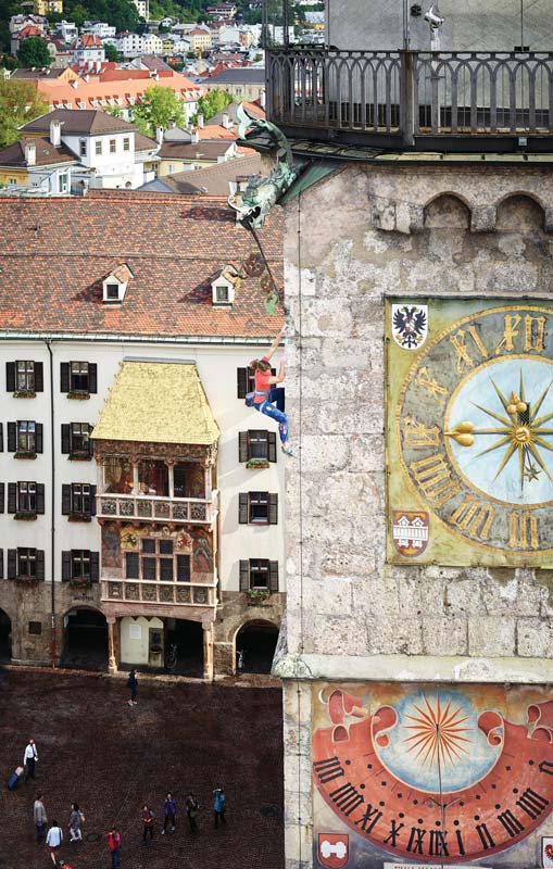 Das Bild zeigt eine Szene zum Thema "Klettern Innsbruck", eine Klettererin am Stadtturm mit Goldenem Dachl im Hintergrund.