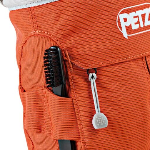 Das Bild zeigt eine Bürstenhalterung und den Reißverschluss an einem orangen Chalkbag mit Tasche.