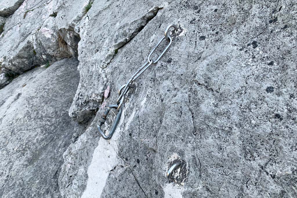 Kettenstand und Klebehaken in grauer Felswand in Klettergarten in Arco.