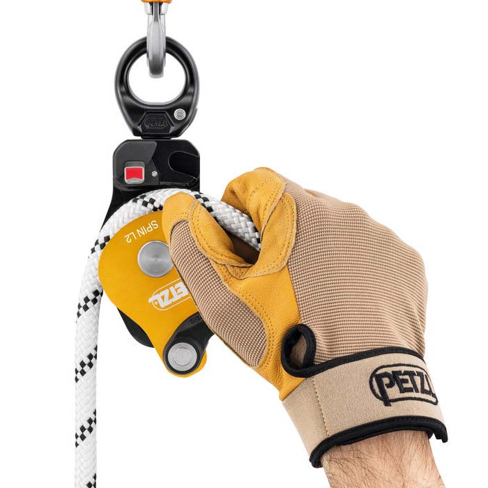 Hand mit Handschuh beim Einhängen eines Seils in eine Petzl Spin L2 Rolle.