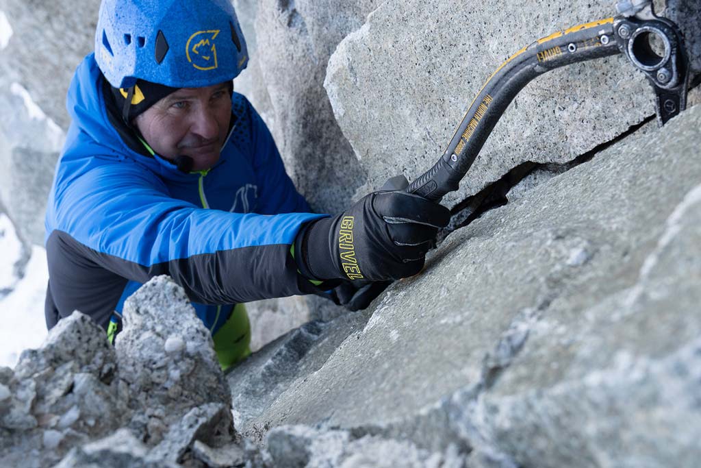 Alpinist mit Eisgerät und den schwarzen Grivel Vertigo Eiskletterhandschuhen im Mixed Gelände.
